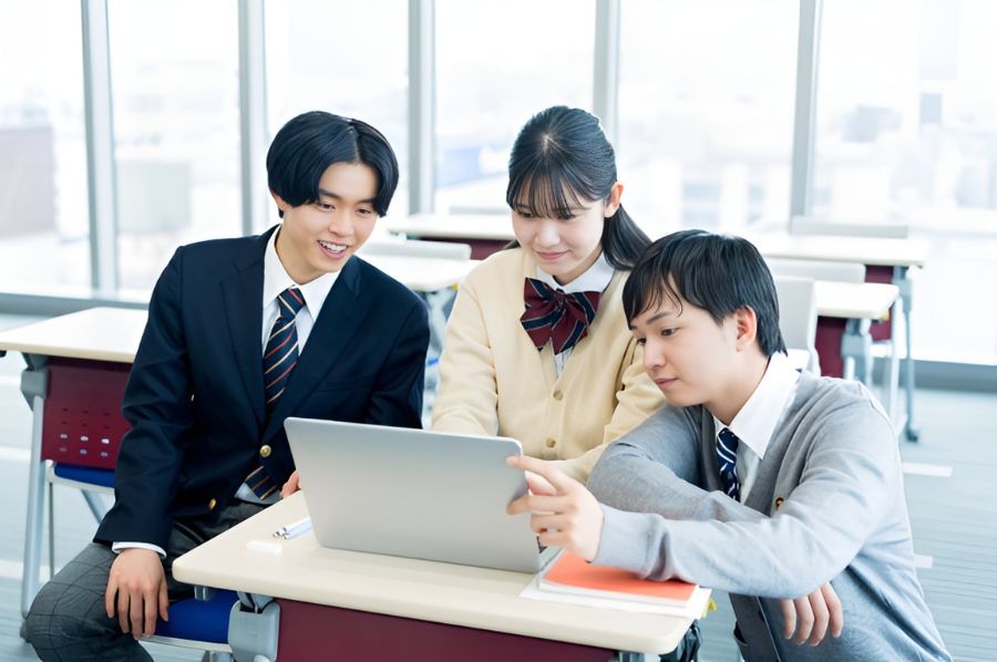 パソコンを眺めながら会話する高校生たち