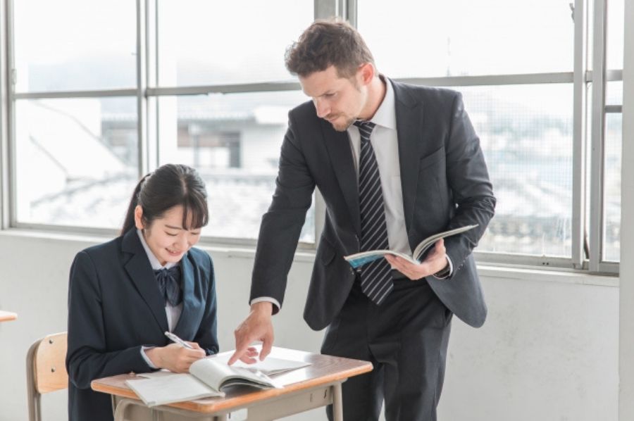 勉強を教える教師と笑顔の女子高生