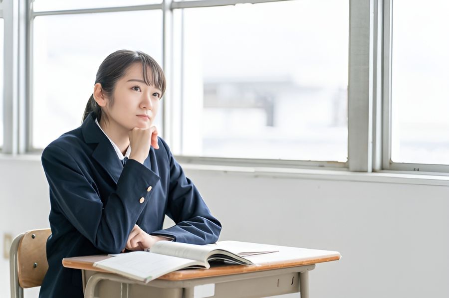 手に顎を置いて考える女子高生