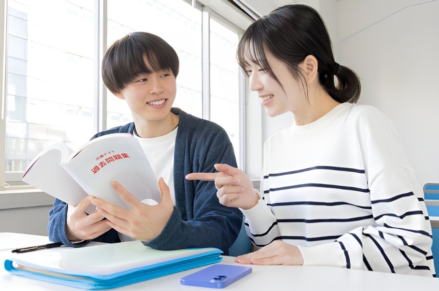 テキストを開いて会話する私服の生徒