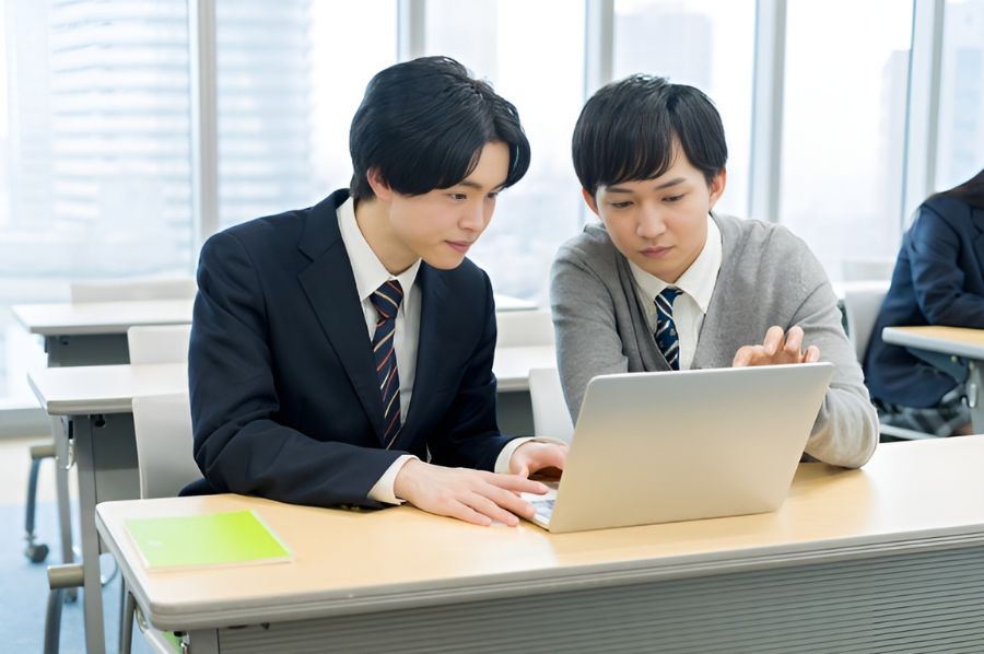 パソコンを眺めながら話す2人の男子高生